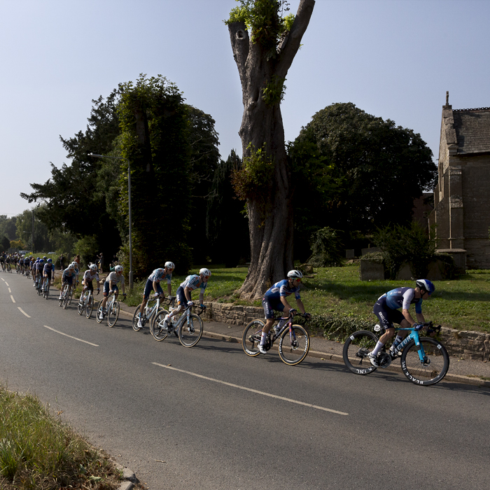 Tour of Britain 2024 - A strung out peloton passes by the church in Egmanton outside Newark on Trent