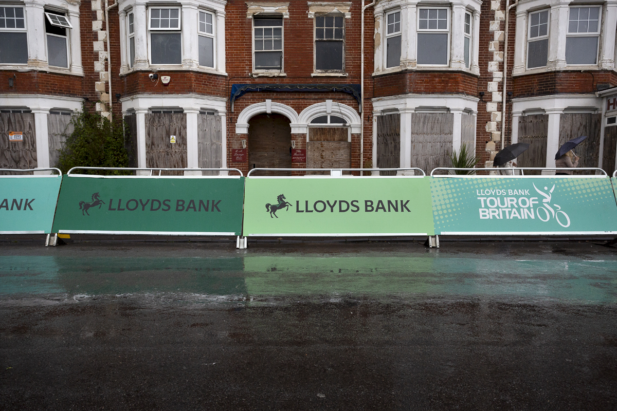 Tour of Britain 2024 - Advertising Hoardings in the rain against empty buildings at the end of the race in Felixstowe