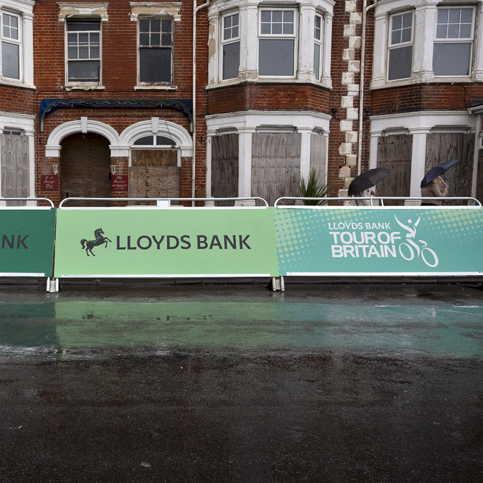 Tour of Britain 2024 - Advertising Hoardings in the rain against empty buildings at the end of the race in Felixstowe