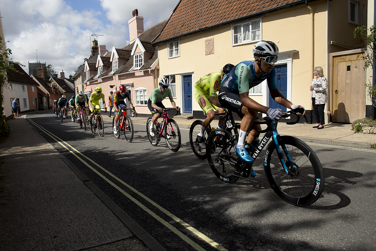 Tour of Britain 2024 - Riders pass by brightly coloured cottages in the village of Framlingham