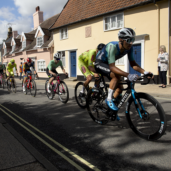 Tour of Britain 2024 - Riders pass by brightly coloured cottages in the village of Framlingham