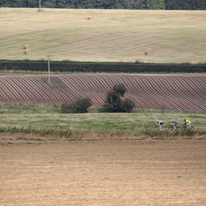 Tour of Britain 2024 - The breakaway followed closely by a camera bike traverses the arable fields of the Scottish Borders