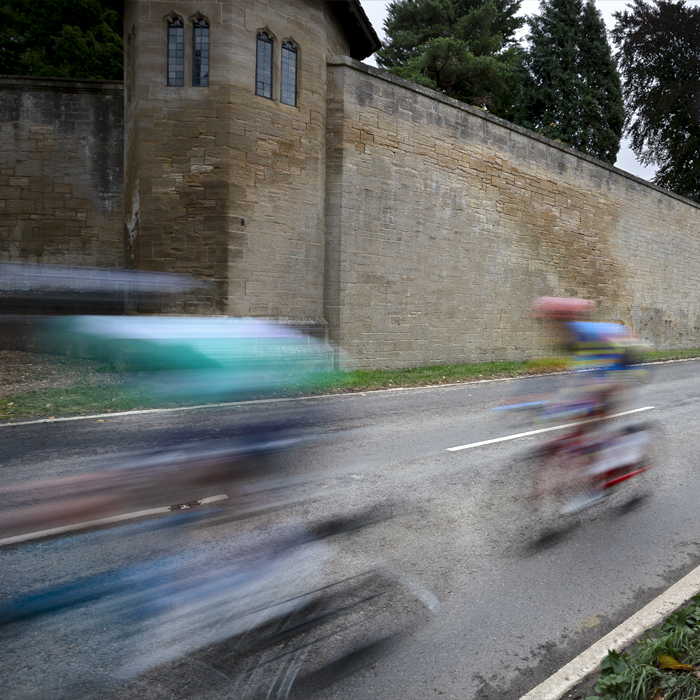 Tour of Britain 2024 - The peloton speed past the austere walls of Hooton Pagnell Hall on their way into the village