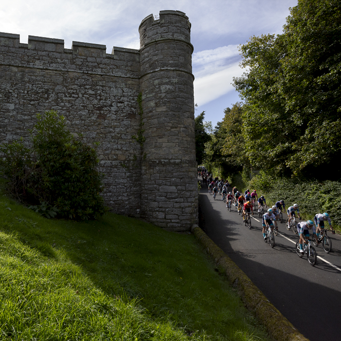 Tour of Britain 2024 - The peloton passes the battlements of Jedburgh Castle and Jail