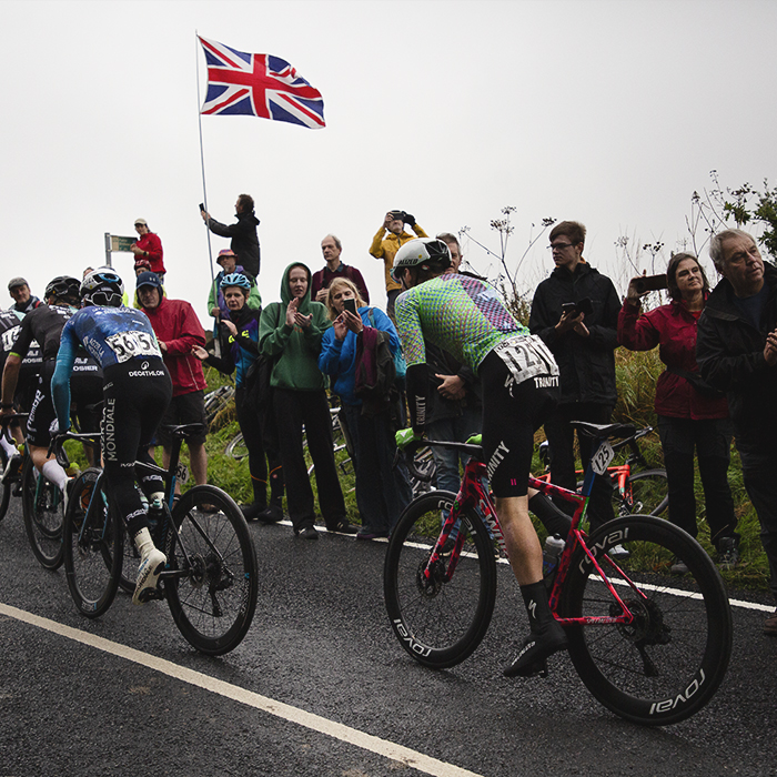 Tour of Britain 2024 - Riders pass fans waving a Union Jack on their way to the top of the Long Lane climb