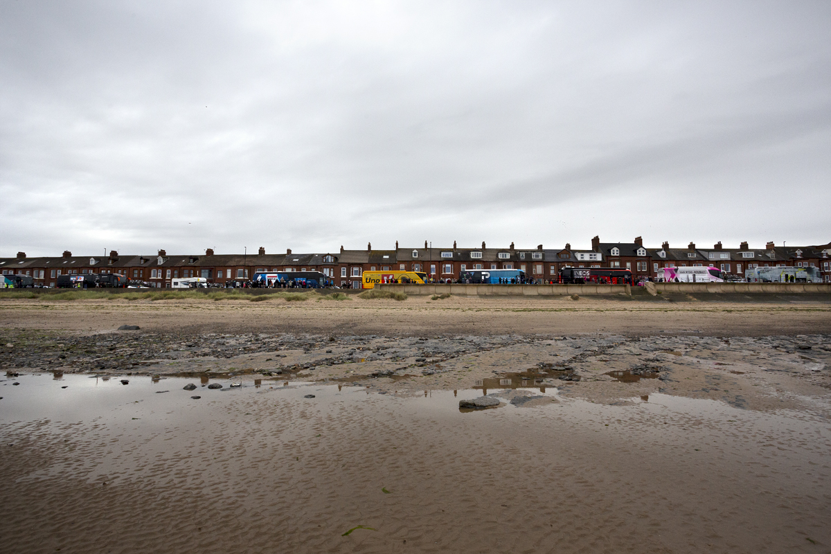 Tour of Britain 2024 - The team buses line up along the seafront at Redcar with the beach in the foreground