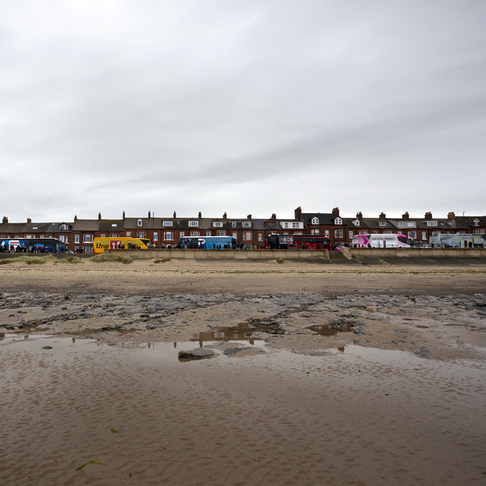 Tour of Britain 2024 - The team buses line up along the seafront at Redcar with the beach in the foreground