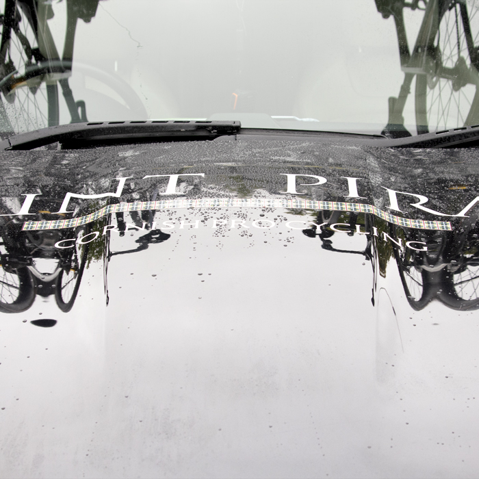 Tour of Britain 2024 - Bikes reflected on the rain spattered bonnet of the Saint Piran team car