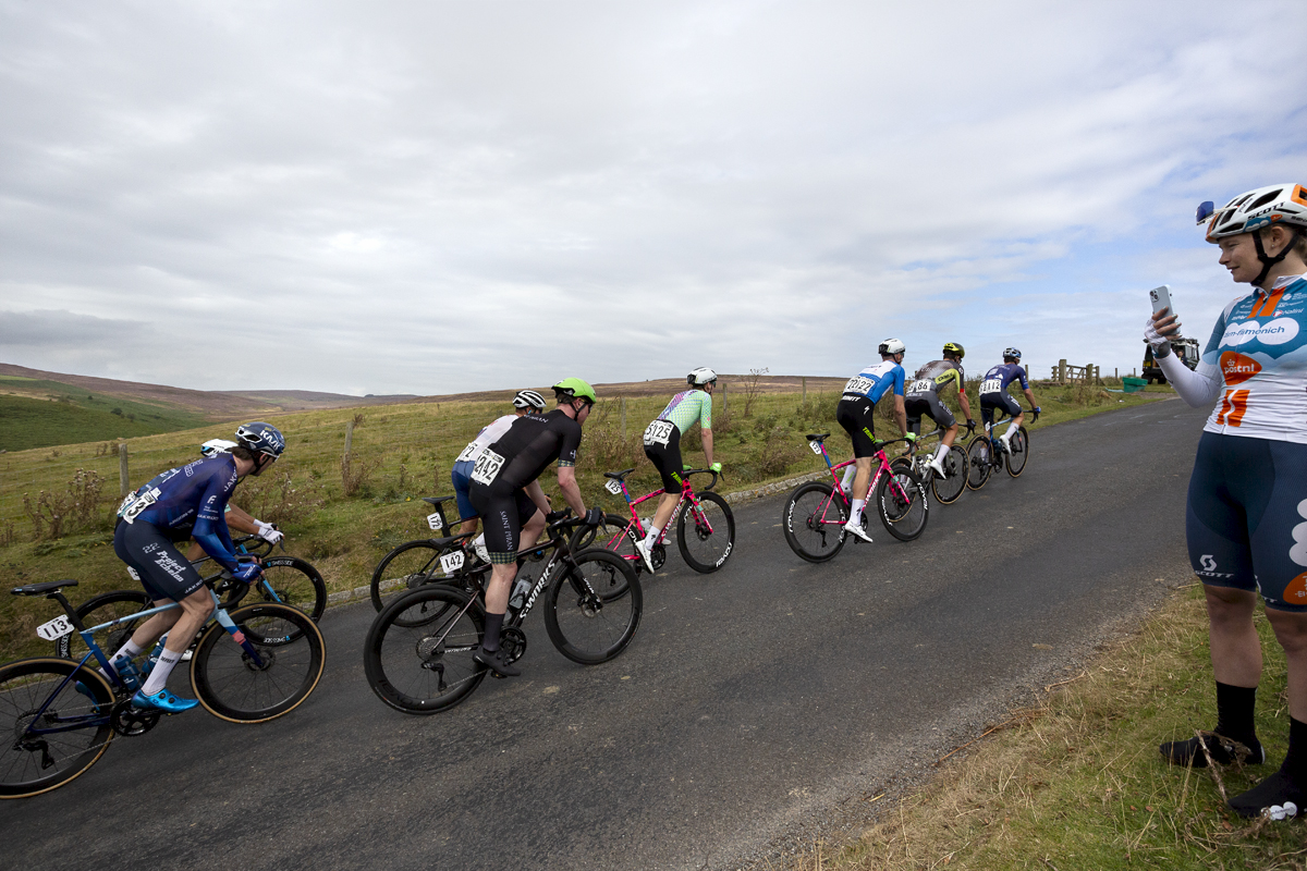 Tour of Britain 2024 - A group of riders pass Women’s World Tour rider Abi Smith of Team dsm-firmenich PostNL who watches the race