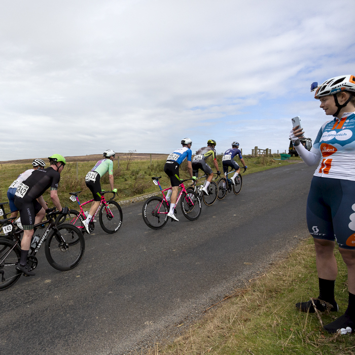 Tour of Britain 2024 - A group of riders pass Women’s World Tour rider Abi Smith of Team dsm-firmenich PostNL who watches the race