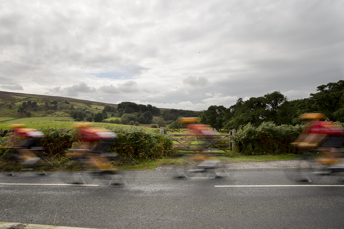 Tour of Britain 2024 - Riders rush past a five bar gate in the North York Moors National Park