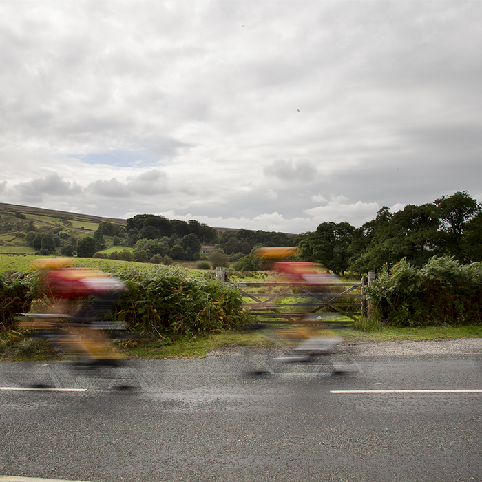 Tour of Britain 2024 - Riders rush past a five bar gate in the North York Moors National Park