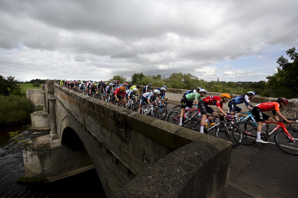 Tour of Britain 2024 - The peloton crosses Teviot Bridge on its approach to the finish in the Scottish Borders