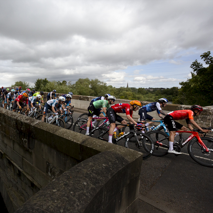 Tour of Britain 2024 - The peloton crosses Teviot Bridge on its approach to the finish in the Scottish Borders