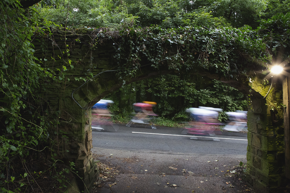 Tour of Britain 2024 - Riders speed past a stone archway close to Wentworth Castle