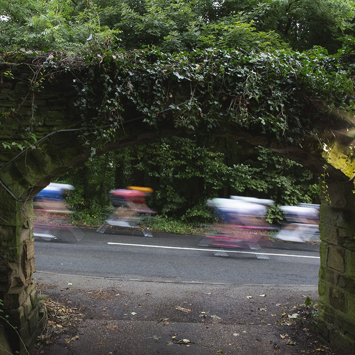 Tour of Britain 2024 - Riders speed past a stone archway close to Wentworth Castle