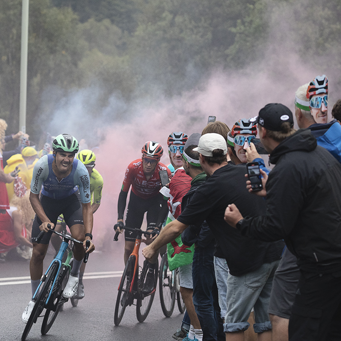 Tour of Britain 2025 - A group of riders make their way up Caerphilly Mountain cheered on by fans wearing Geraint Thomas masks
