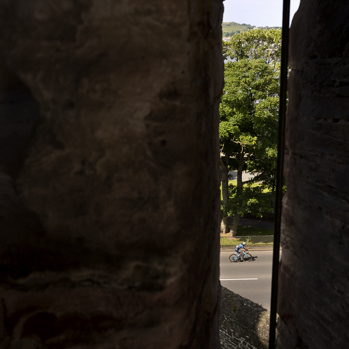 Tour of Britain Women’s 2024 - A rider is framed by one of the arrow slits in Conwy Castle