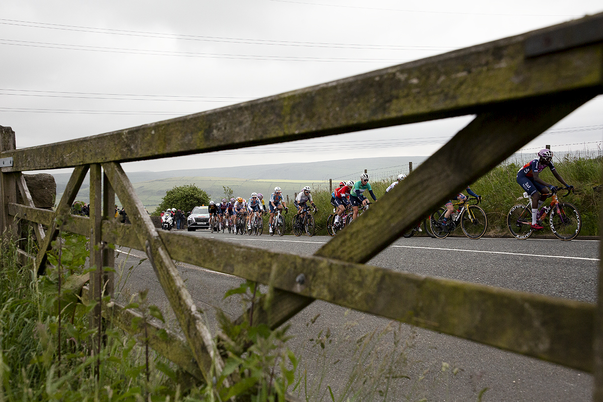 Tour of Britain Women’s 2024 - The race seen through a five bar gate as it makes its way up the climb