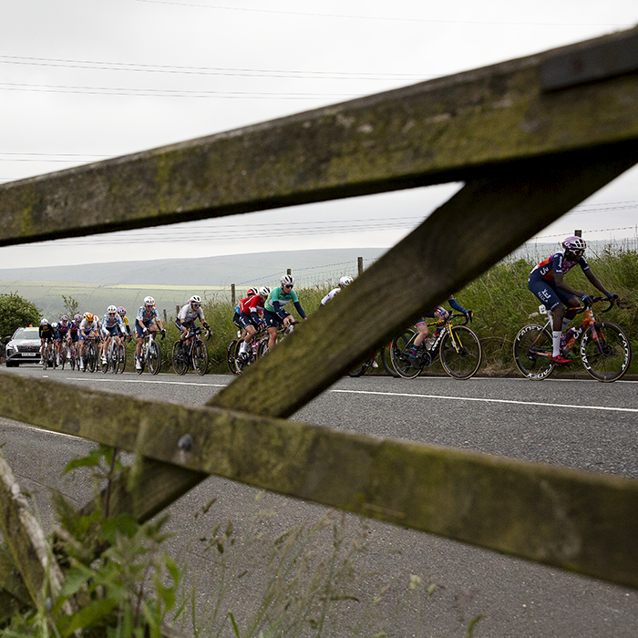 Tour of Britain Women’s 2024 - The race seen through a five bar gate as it makes its way up the climb