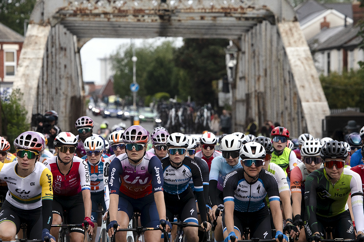 Tour of Britain Women’s 2024 - The peloton with a rusty iron bridge behind them