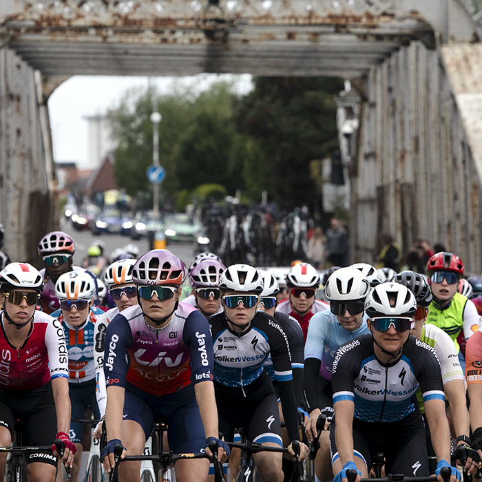 Tour of Britain Women’s 2024 - The peloton with a rusty iron bridge behind them 