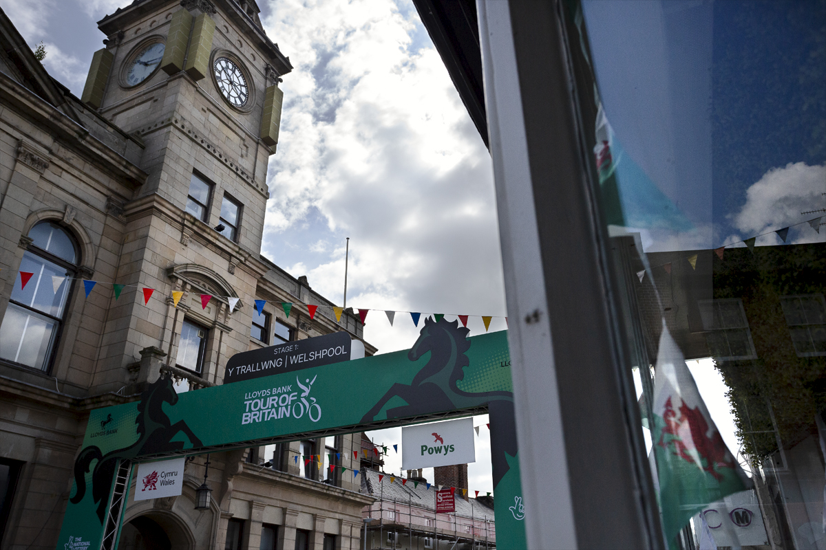 Tour of Britain Women’s 2024 - Welshpool Town Hall and the start gate with Wales bunting in a shop window