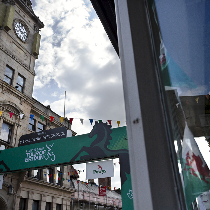 Tour of Britain Women’s 2024 - Welshpool Town Hall and the start gate with Wales bunting in a shop window