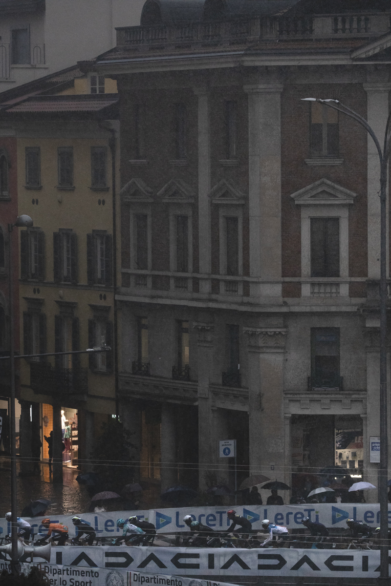 A few hardy souls watch from under umbrellas and in shop doorways as the peloton passes majestic buildings in Varese.