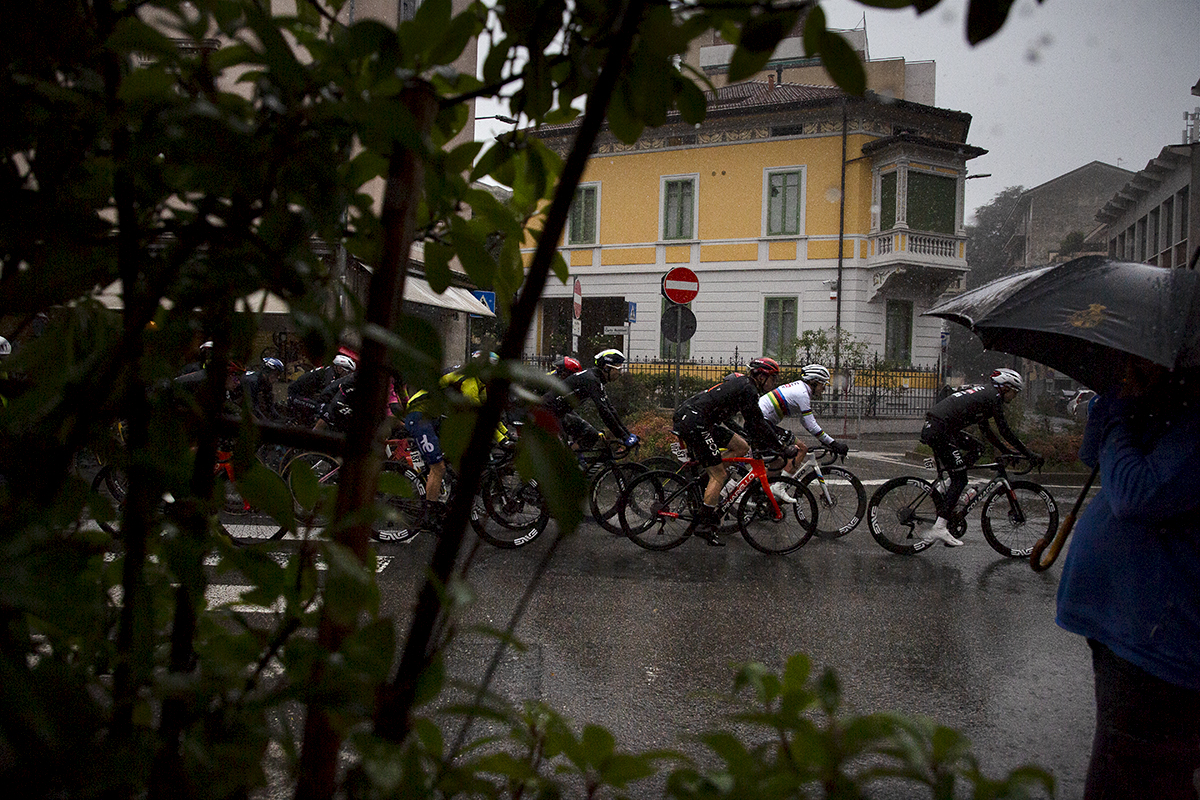 Tre Valli Varesine 2024 - Riders pass by a spectator huddled under an umbrella during the rain soaked race