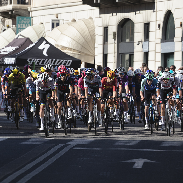 Tre Valli Varesine 2025 - Shop canopies can be seen in the background as the peloton rides through Varese