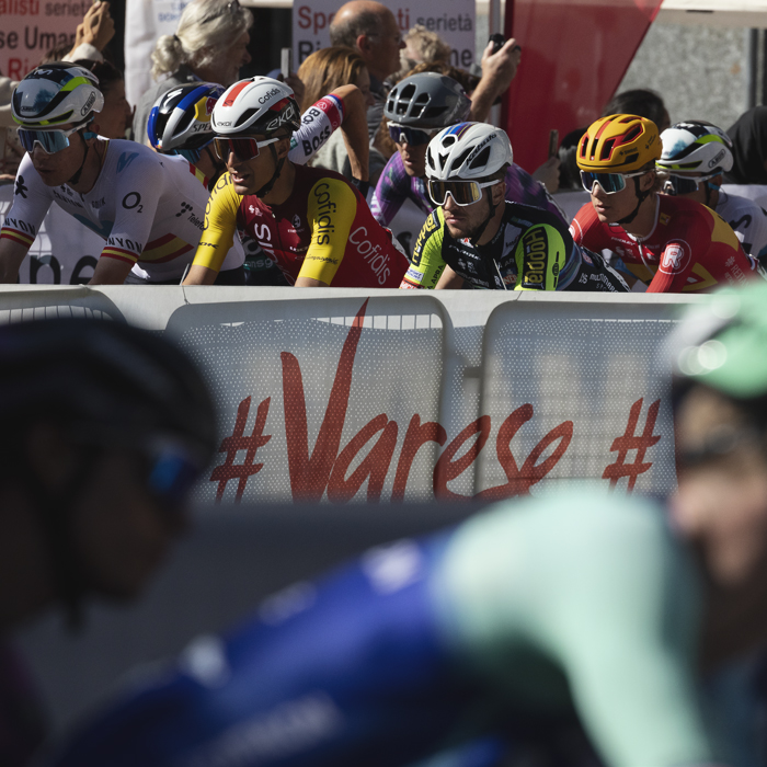 Tre Valli Varesine 2025 - Riders pass by an advertising hoarding bearing the word Varese