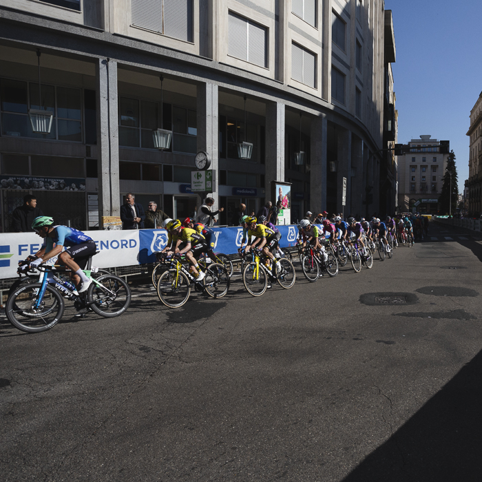 Tre Valli Varesine 2025 - Riders pass by commercial buildings in Varese