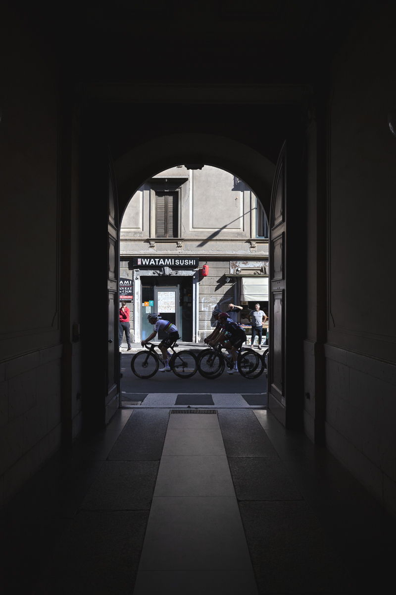Tre Valli Varesine 2025 - Riders viewed through an archway
