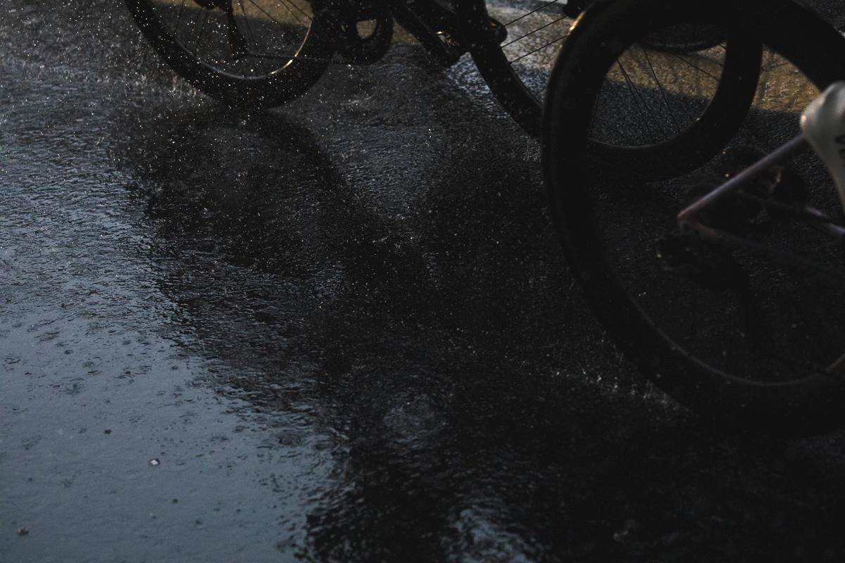 Tre Valli Varesine Women’s Race 2024 - The shadow of a bike wheel with spray coming up from its wheel in Varese