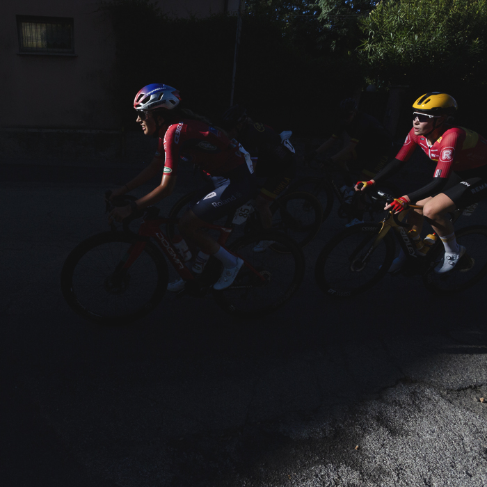 Tre Valli Varesine Women’s Race 2025 - Riders emerge from deep shadows their faces caught by bright sunlight