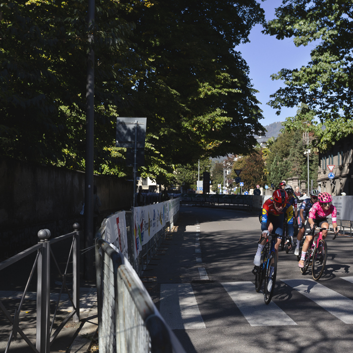 Tre Valli Varesine Women’s Race 2025 - A group of riders round a corner on a tree lined street