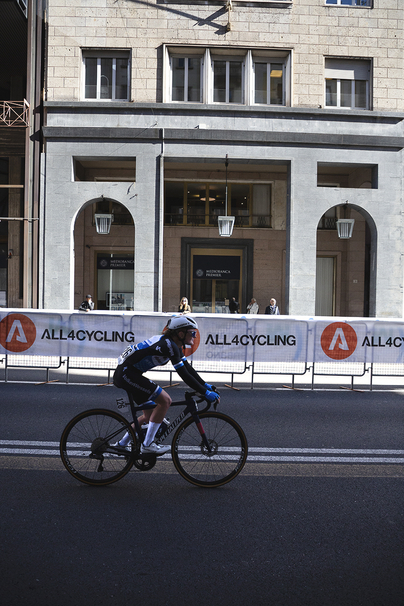 Tre Valli Varesine Women’s Race 2025 - A smiling Malou Eisen rides past shops in the arcades of Varese