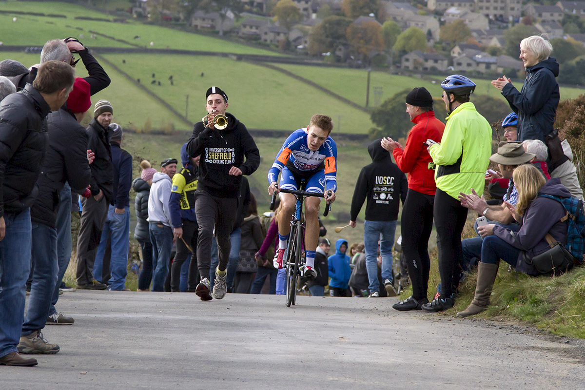 UK National Hill Climb Championships 2015 - A fan playing a small trombone runs alongside James Hill on the climb