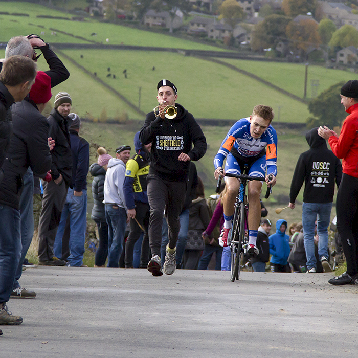 UK National Hill Climb Championships 2015 - A fan playing a small trombone runs alongside James Hill on the climb