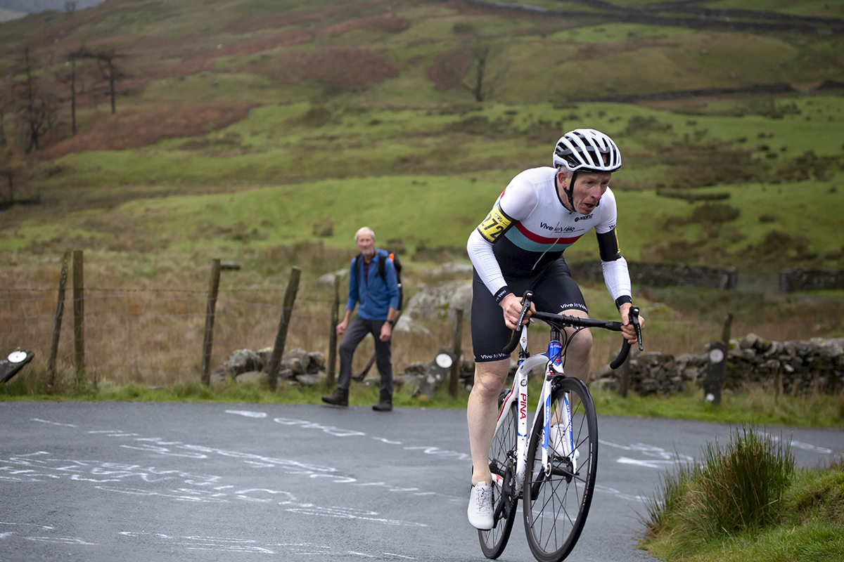 UK National Hill Climb Championships 2023 - Andrew Askwith rounds a hairpin on the climb with writing showing support on the road