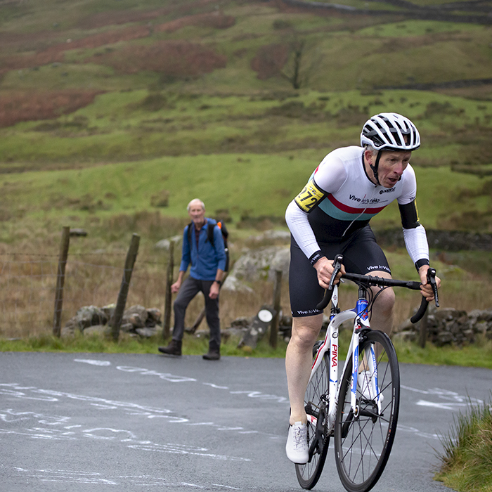 UK National Hill Climb Championships 2023 - Andrew Askwith rounds a hairpin on the climb with writing showing support on the road