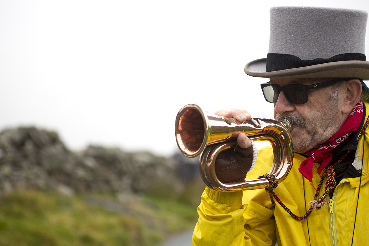 UK National Hill Climb Championships 2023 - A fan wearing a top hat and yellow jacket plays the bugle