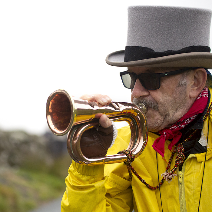 UK National Hill Climb Championships 2023 - A fan wearing a top hat and yellow jacket plays the bugle