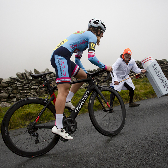 UK National Hill Climb Championships 2023 - Charlotte Dalton passes a supporter wearing a lab coat wielding a giant inhaler marked Salbutamol