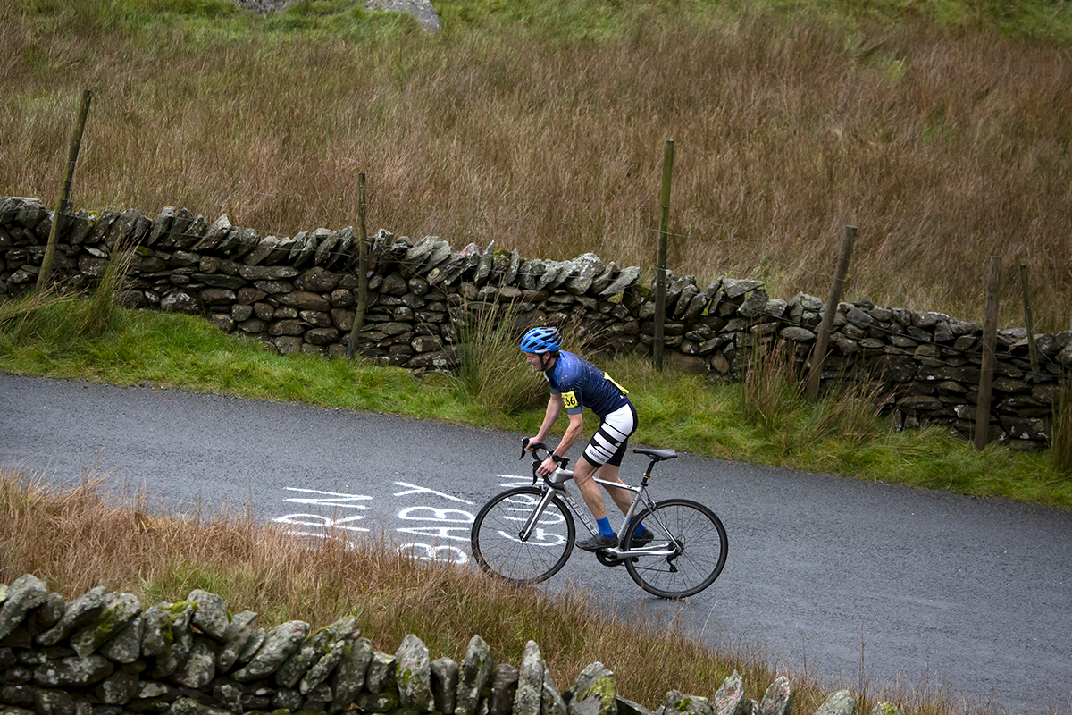 UK National Hill Climb Championships 2023 - James Warner Smith rides over writing reading Gurn Baby Gurn on his way up the climb