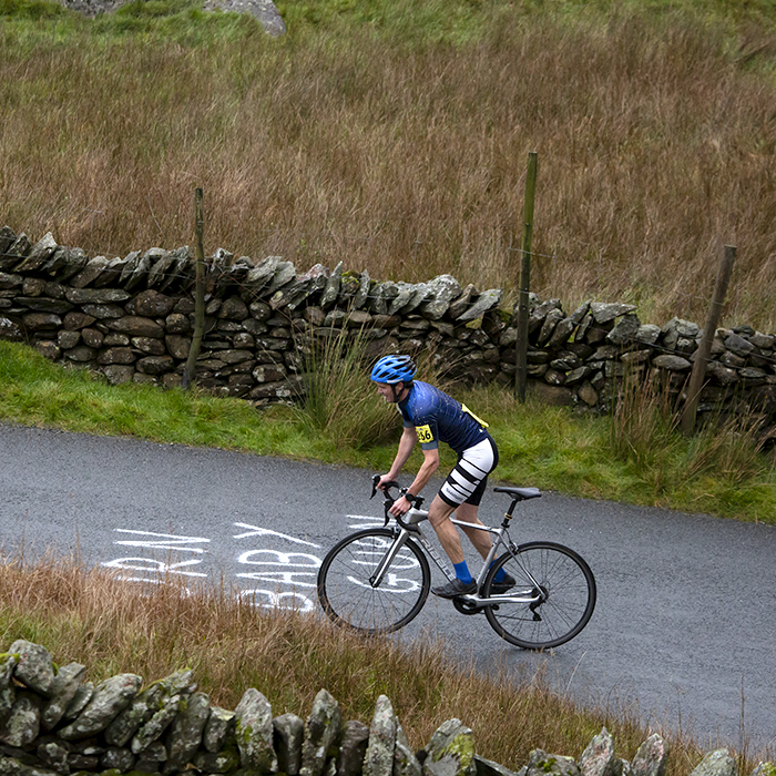 UK National Hill Climb Championships 2023 - James Warner Smith rides over writing reading Gurn Baby Gurn on his way up the climb