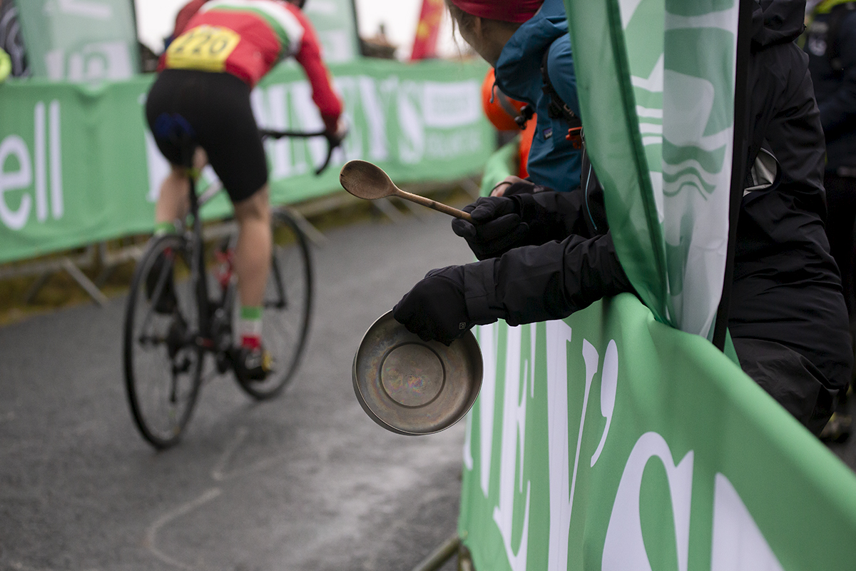 UK National Hill Climb Championships 2023 - A fan bangs a pan with a wooden spoon as a rider nears the finish