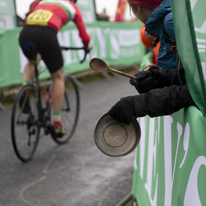 UK National Hill Climb Championships 2023 - A fan bangs a pan with a wooden spoon as a rider nears the finish