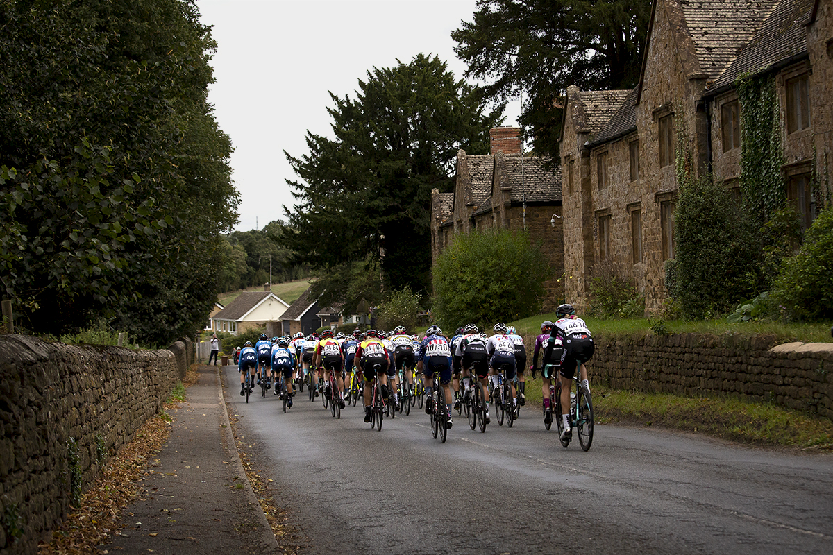 Women’s Tour 2021 - The peloton moves away through Broughton in Oxfordshire past traditional stone cottages